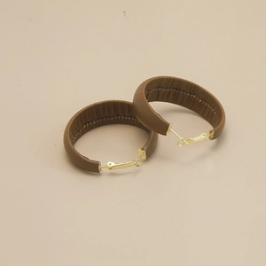 Vintage brown leather hoop earrings with gold metal details on a minimalist background
