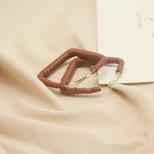 Detailed macro view of large rectangular earrings with brown leather winding texture