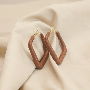 Detail of brown leather textured rectangular hoop earrings with polished gold metal
