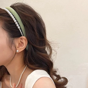 Détail du serre-tête rembourré vert clair avec perles blanches sur un mannequin femme