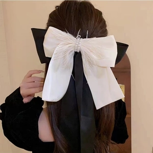 Detail of elegant black and white bow hair clip with pearls and feather accents