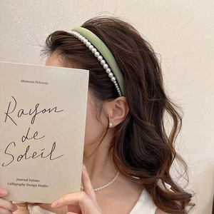Détail montrant la texture satinée vert clair et les perles sur le serre-tête double