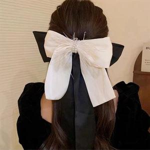 Detail of the elegant double-layer bow hair clip with pearls and feather accents