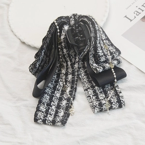 Détail d'une pince à cheveux en tweed avec chaîne de perles et breloques dorées
