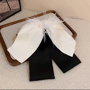 Detail of elegant bow hair clip with white feathers, imitation pearls, and black fabric