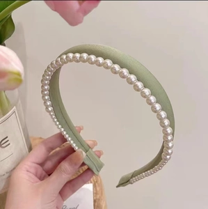 Vue détaillée du serre-tête en satin vert clair orné d'élégantes perles blanches