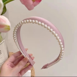Vue détaillée d'un serre-tête en satin rose avec perles blanches et tissu élégant