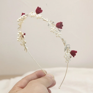 Détail d'un serre-tête doré avec fleurs en velours rouge, perles et cristaux fins