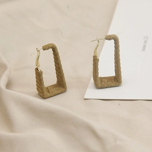 Macro detail of khaki rectangular leather hoop earrings with twisted texture and gold hooks