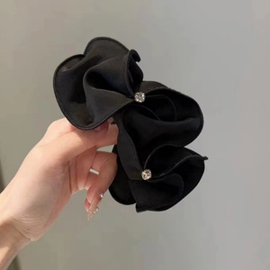 Macro detail of black satin pleated scrunchie hair tie with sparkling rhinestone accents