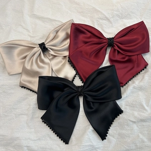 Détail de grandes barrettes à nœuds en satin avec bordure en perles de cristal colorées