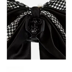 Detail of houndstooth and satin bow hair clip with a center white pearl accent