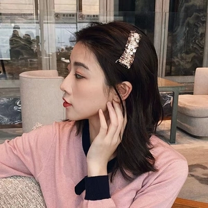 Vue détaillée d'une barrette à fleurs dorées avec perles blanches sur les cheveux
