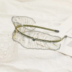 Detailed view of woven green crystal headband with handmade beaded feather motifs