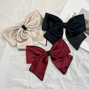 Gros plan sur des barrettes nœuds en satin de couleurs beige, noir et bordeaux