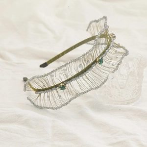 Detail view of woven green wire headband with emerald gemstones and micro beads