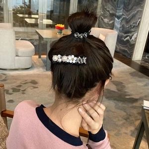 Détail d'une barrette à cheveux avec perles et fleurs portée pour un look élégant