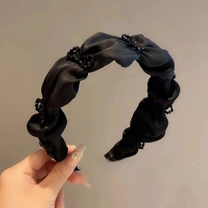 Close-up of black satin pleated headband featuring elegant beaded accents for women