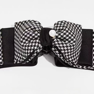 Close-up of houndstooth pattern bow hair claw clip with central pearl ornament