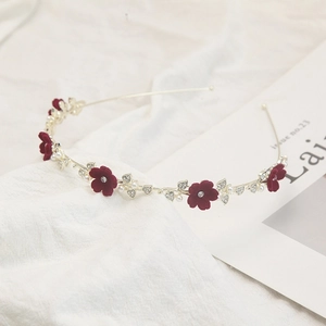 Détail d'un bandeau doré élégant avec fleurs en velours rouge, perles et cristaux