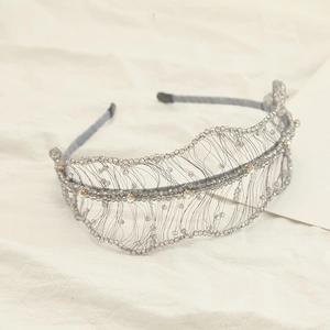 Macro detail of hand-woven crystal bead headband with grey feather-like wire embroidery