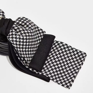 Detail of multi-layered houndstooth bow hair claw clip with rich fabric texture