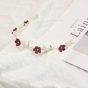 Détail de fleurs en velours rouge, perles et feuilles en cristal sur un serre-tête doré