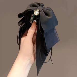 Détail d'une pince à cheveux à nœud noir avec grande perle et longs rubans pour femmes