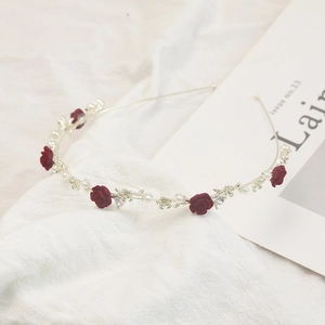 Détail d'un serre-tête fin avec des roses en velours rouge foncé, perles blanches et cristaux