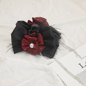 Detail of black satin bow hair claw featuring wine red flowers and silver rhinestone tassels