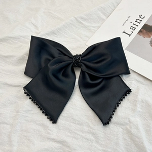 Détail d'un nœud papillon en satin noir élégant orné de perles noires sur fond blanc