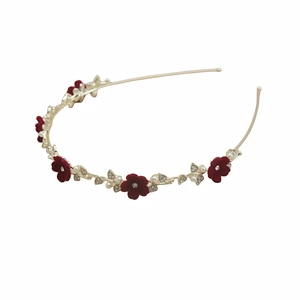 Détail de serre-tête doré élégant avec fleurs floquées rouges, perles et cristaux