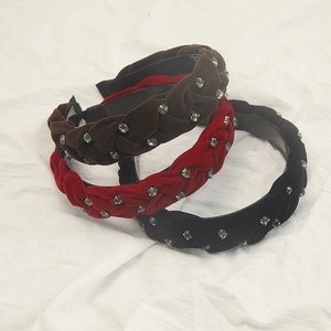 Dettaglio di tre cerchietti in velluto intrecciato con strass nei colori marrone, rosso e nero