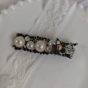 Détail de la barrette en tweed avec perles blanches et camélia noir sur de la dentelle