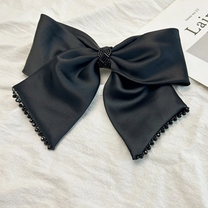 Détail de la grande pince à cheveux nœud en satin noir mat avec perles et nœud central
