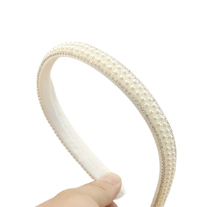 Detailed close-up of cream white headband with three rows of pearls and rhinestones