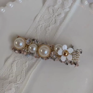 Barrette en tweed élégante avec fleurs, perles et strass sur fond de dentelle blanche