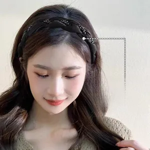 Détail du serre-tête tressé en satin noir avec strass pour un effet de volume haut