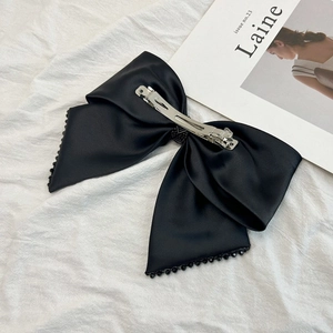Détail d'un nœud papillon en satin noir avec perles sur fond de magazine élégant