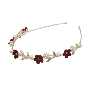 Détails macro de fleurs en tissu bordeaux et perles blanches sur un serre-tête doré