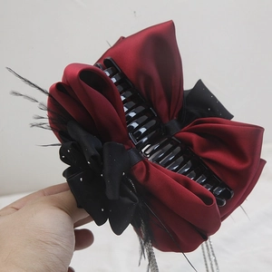 Elegant bow hair claw with black feathers, burgundy satin, and silver tassel chains
