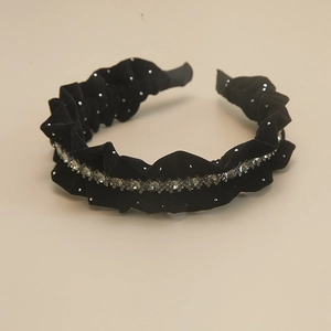 Close-up of black velvet headband featuring ruffles and sparkling rhinestone details