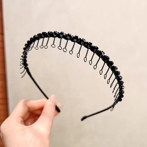 Vue détaillée d'un serre-tête en strass noirs avec crochets métalliques et perles polies