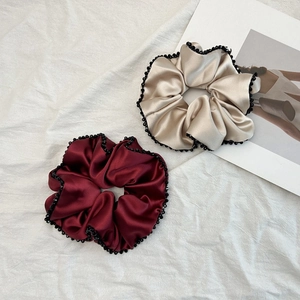 Détail de chouchous en satin champagne et bordeaux avec bords ornés de fines perles