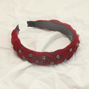Dettaglio di cerchietto trecciato in velluto rosso con strass e denti interni antiscivolo