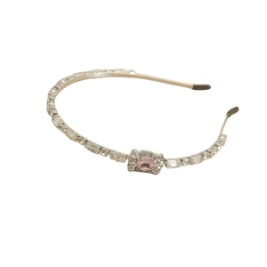 Eleganter Kristall-Haarreif aus Metall mit rosa ovalem Edelstein auf weißem Hintergrund