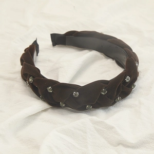 Dettaglio del cerchietto intrecciato in velluto marrone scuro con strass color smeraldo