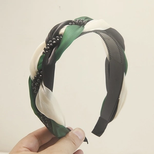 Vue détaillée du serre-tête tressé en satin avec tissu vert foncé et perles brillantes
