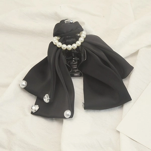 Detailed macro view of black satin bow hair claw clip with pearls and crystal heart charms