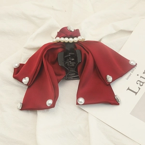 Detail view of burgundy satin bow hair claw with elegant pearls and sparkling rhinestones